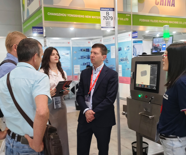 International customer discussing inspection needs with Foodman sales representative at exhibition booth
