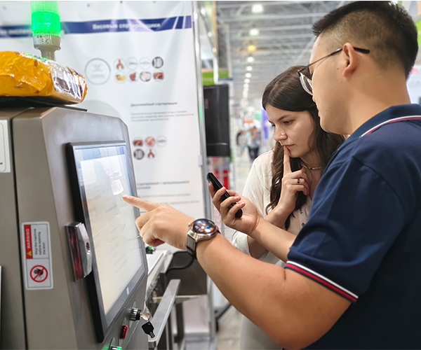 International customer discussing inspection needs with Foodman sales representative at exhibition booth