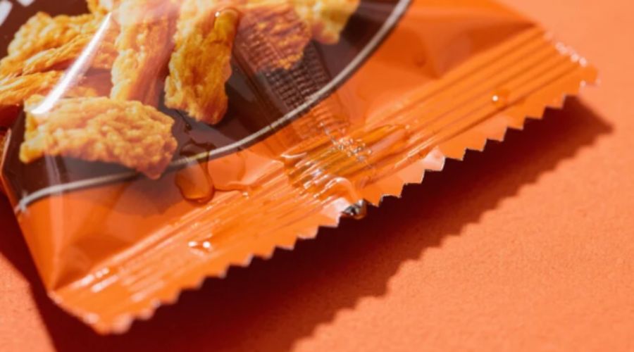 Heat-sealed pouch showing product material trapped in seal edge causing weak seal and potential leakage