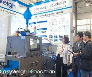 Foodman technical expert explaining X-ray inspection system features to potential customers at exhibition booth