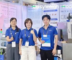 Foodman team group photo at international trade exhibition booth with branded uniforms and inspection equipment display