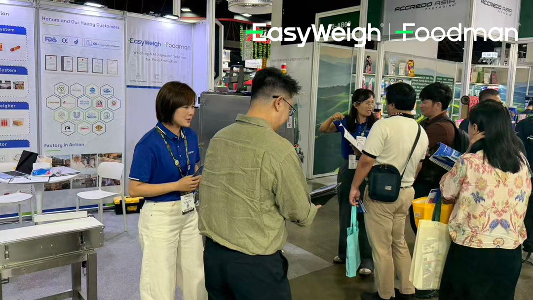 Close-up of visitors examining Foodman inspection equipment specifications and test results